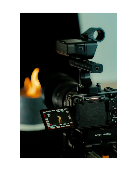 Cinema camera beside a lit candle
