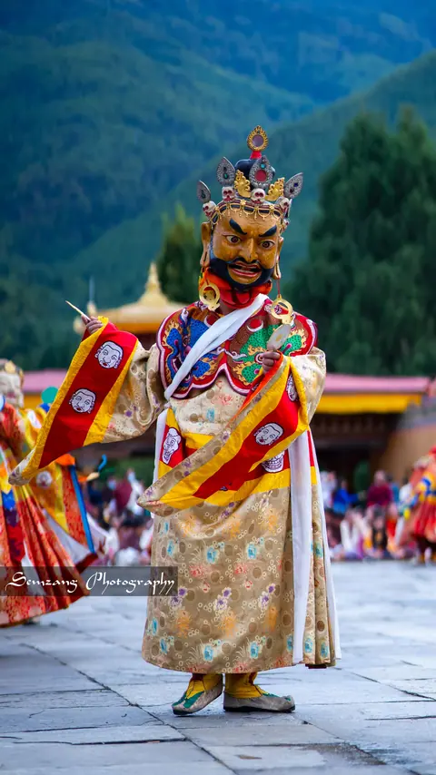 Dancer in a gold costume and ornate crown mask at the festival