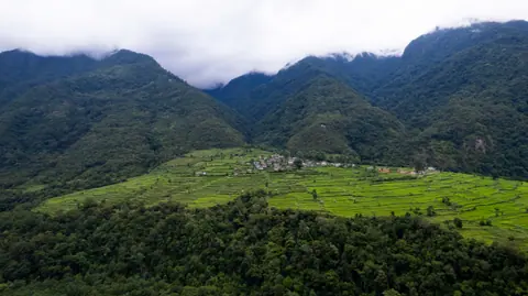 Green mountain ridge and terraced pasture under clouds