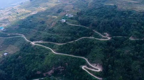 Aerial view of a winding road through forested hills