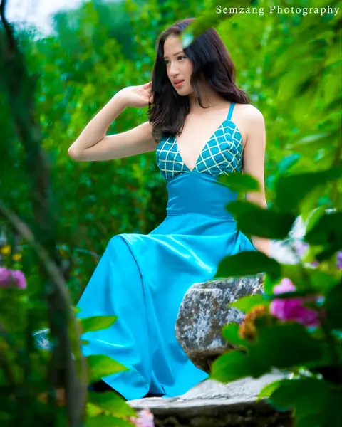 Woman in a turquoise dress among green foliage and flowers