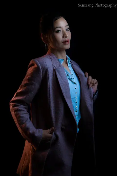 Studio portrait of a woman in a dark blazer against a black background