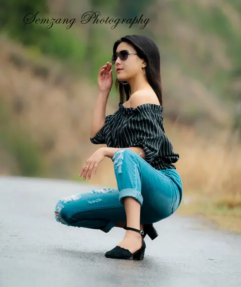 Woman in sunglasses crouching on a country road