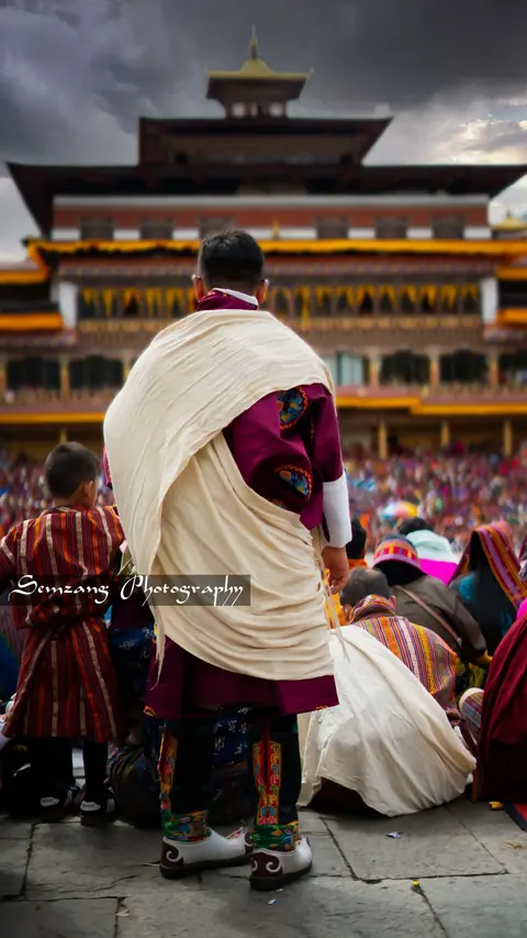 Man in a gho and white scarf at the festival courtyard
