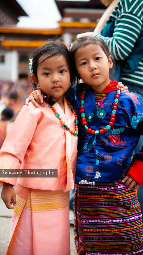 Two young girls in traditional dress with beaded necklaces