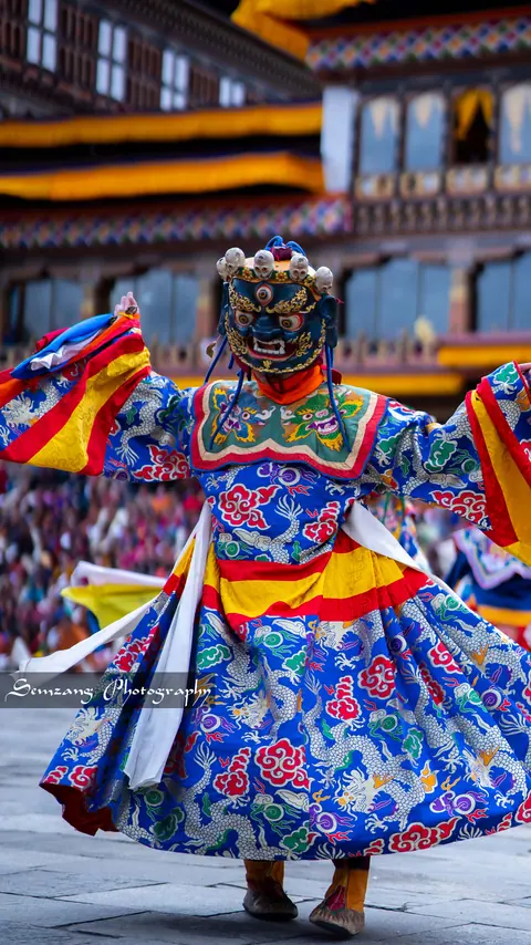 Mask dancer in a blue brocade costume at a Bhutanese festival