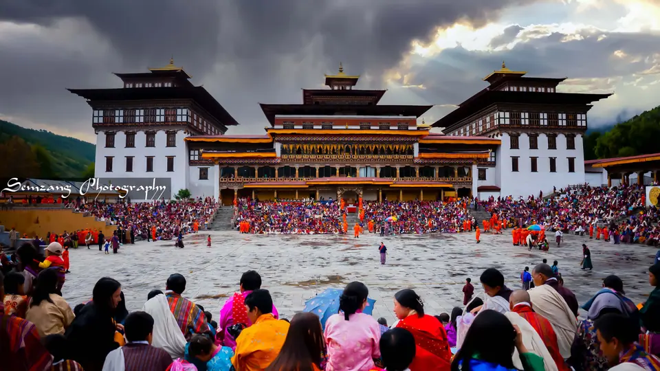 Festival ground in front of a Bhutanese dzong with crowds and dancers